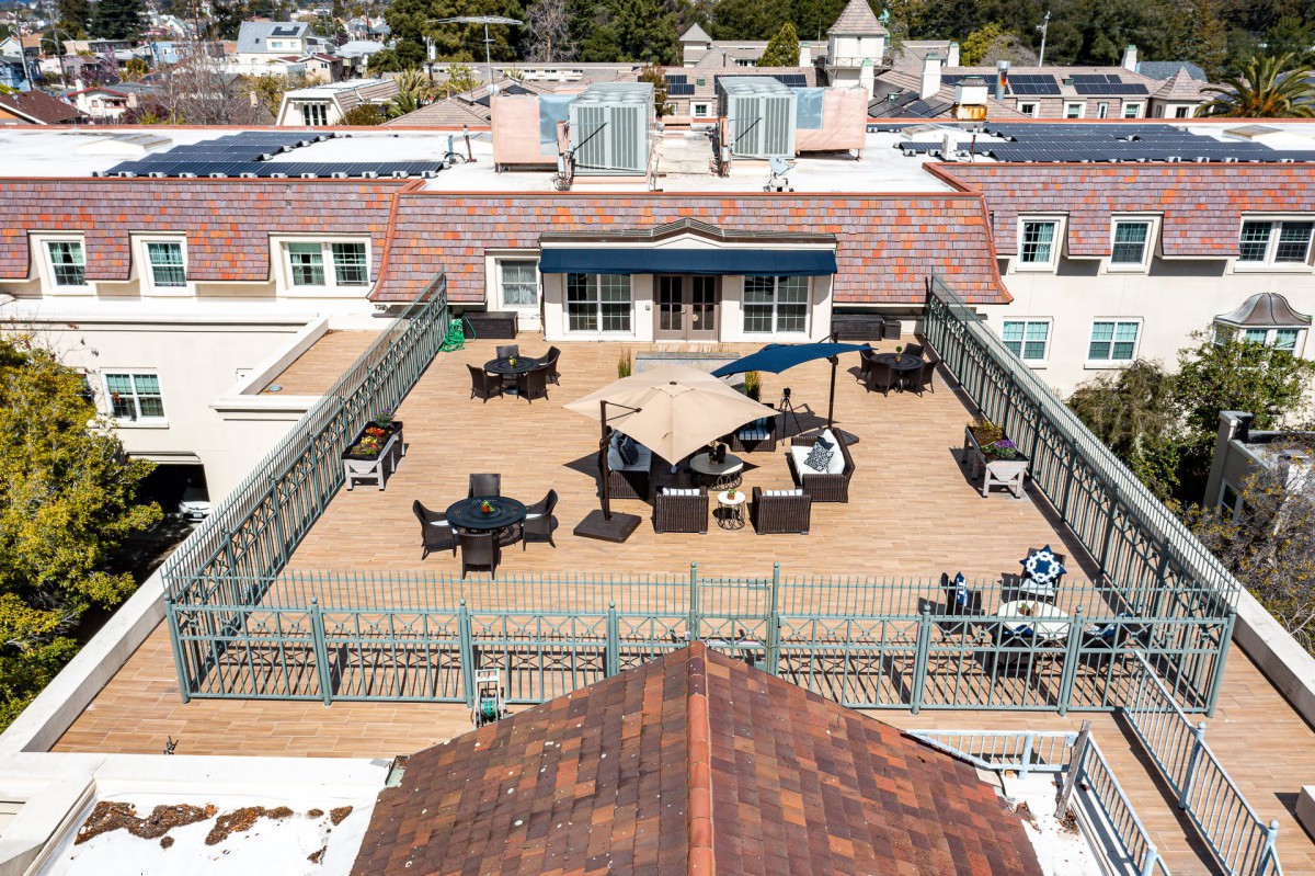A spacious rooftop patio with comfortable seating and umbrellas in an urban environment.