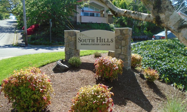 A stone sign for a neighborhood community surrounded by lush greenery and foliage.
