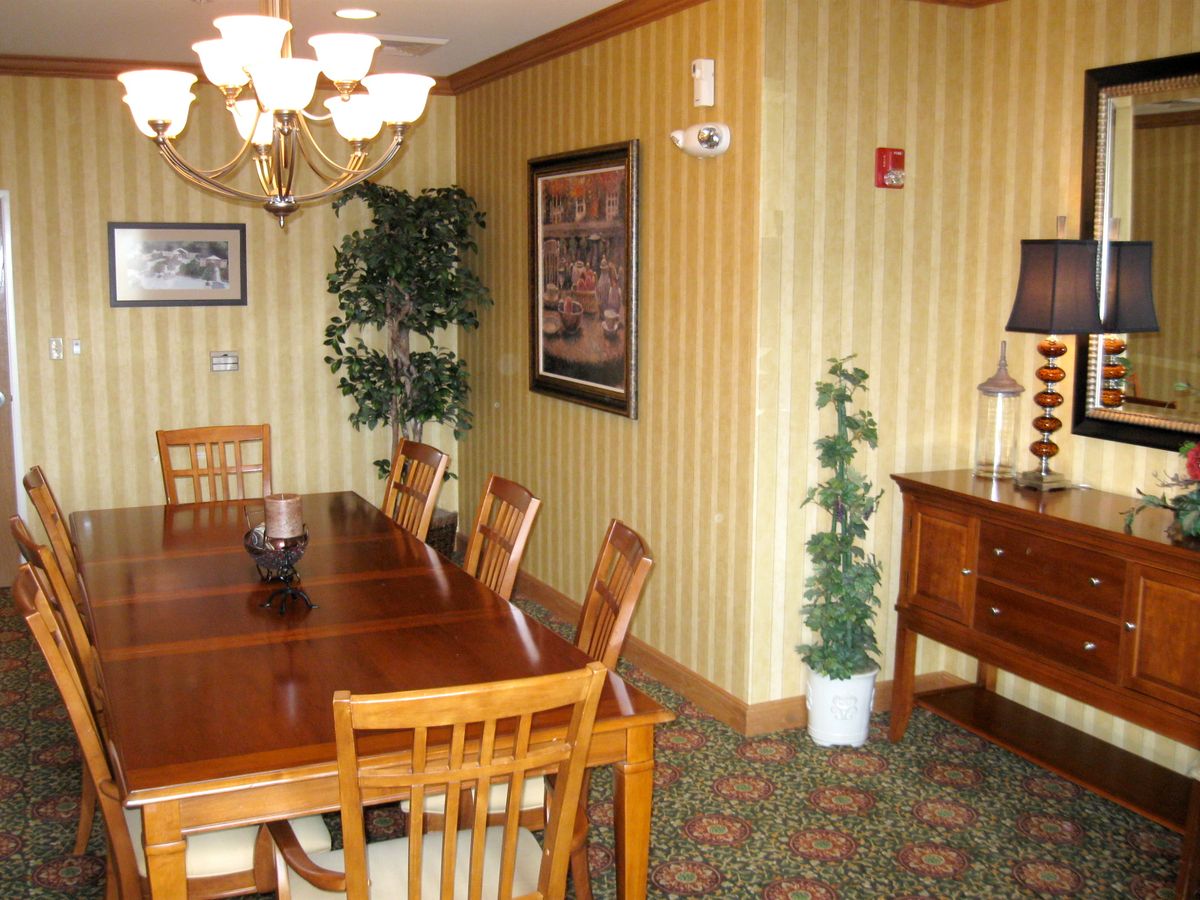 A cozy dining room with a wooden table and chairs, decorated with indoor plants and artwork on the walls.