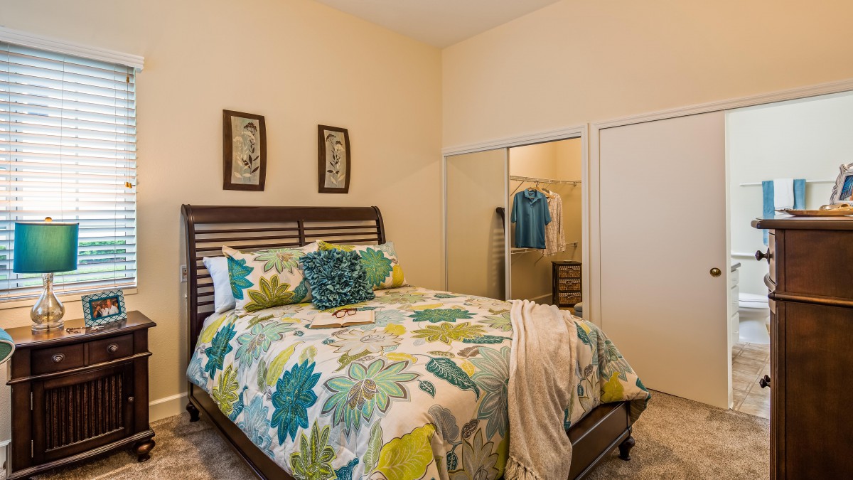 A cozy bedroom with floral bedding and a mirror closet.