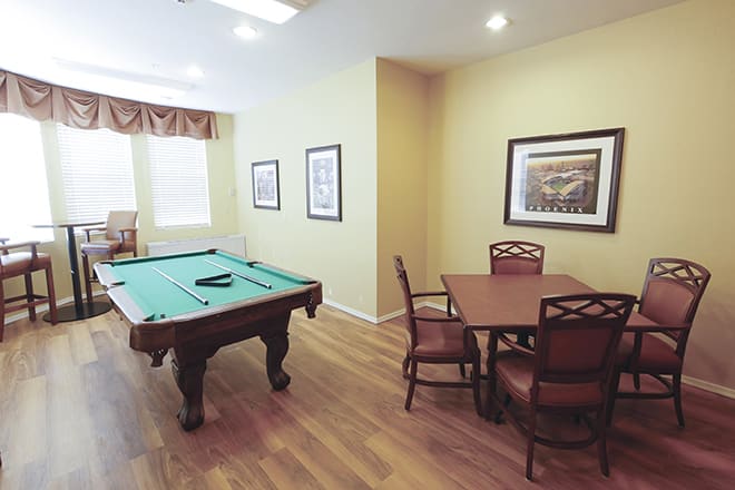A cozy recreation room featuring a pool table and seating area with framed artwork on the walls.