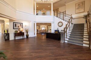 A spacious and elegant lobby with a grand staircase and hardwood flooring.