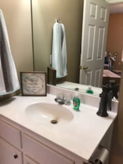 A tidy bathroom countertop with a sink, mirror, and various items.
