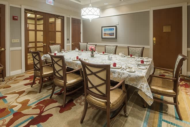 A formal dining room setup with a large table and chairs, elegantly decorated for a gathering.
