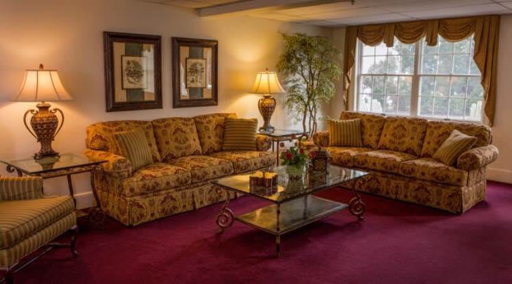 A cozy living room featuring patterned sofas, a glass-top coffee table, and elegant decor.