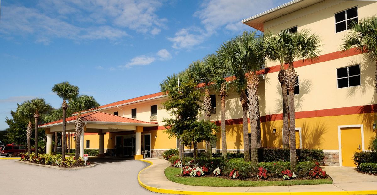 A sunny view of a building surrounded by palm trees and well-maintained landscaping.
