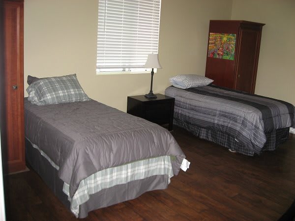 A simple bedroom with two twin beds and a nightstand.