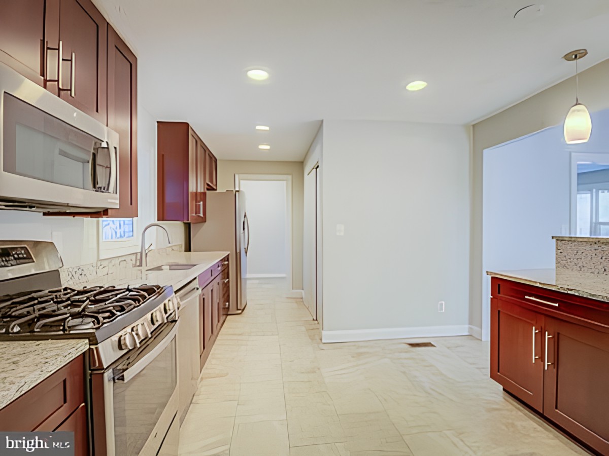 A modern kitchen with stainless steel appliances and recessed lighting.