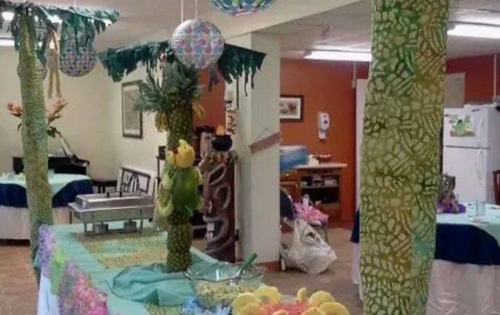 A festive indoor setting with tropical-themed decorations and colorful balloons.