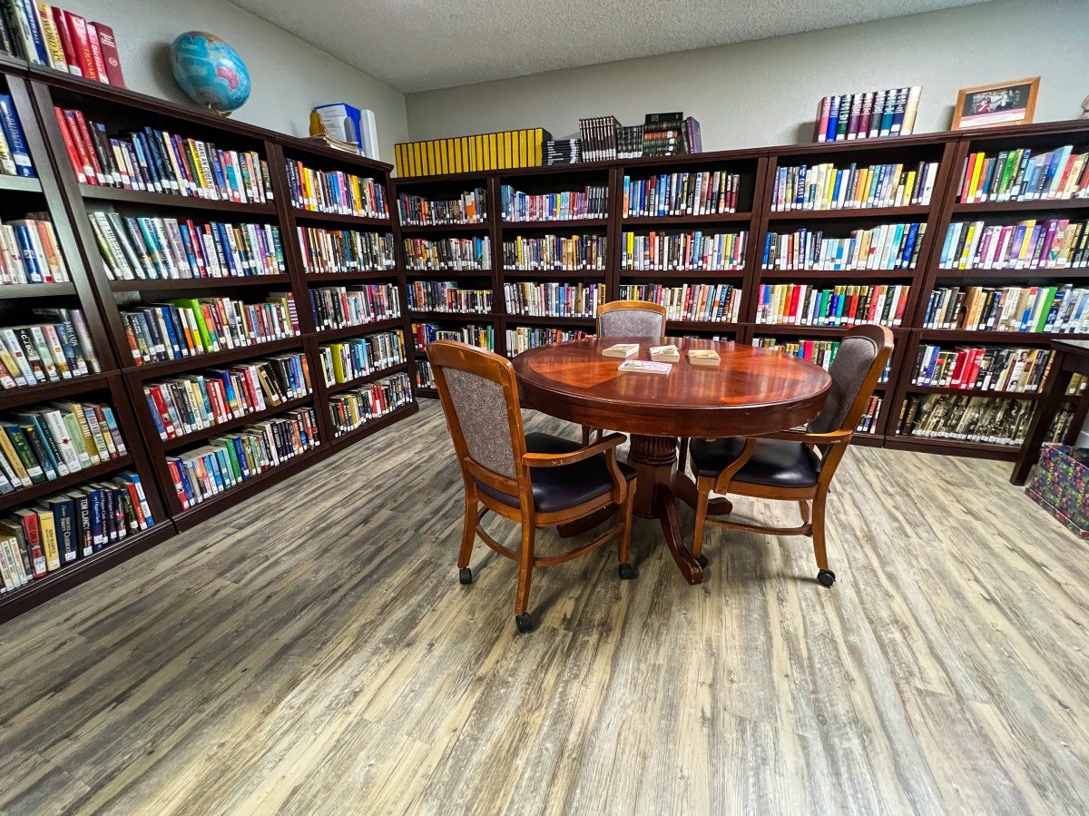 A cozy library corner with bookshelves, a round table, and four chairs.