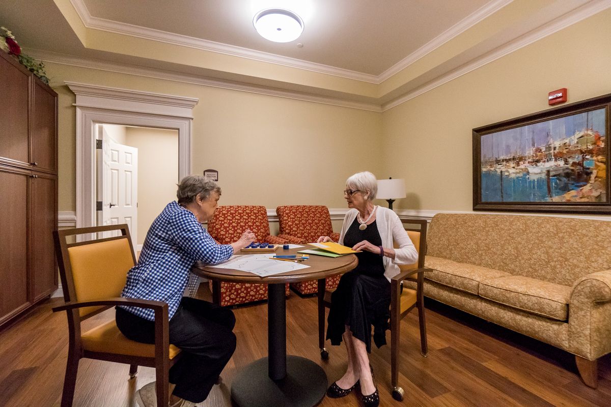 Two people engaged in a conversation at a table in a cozy room.