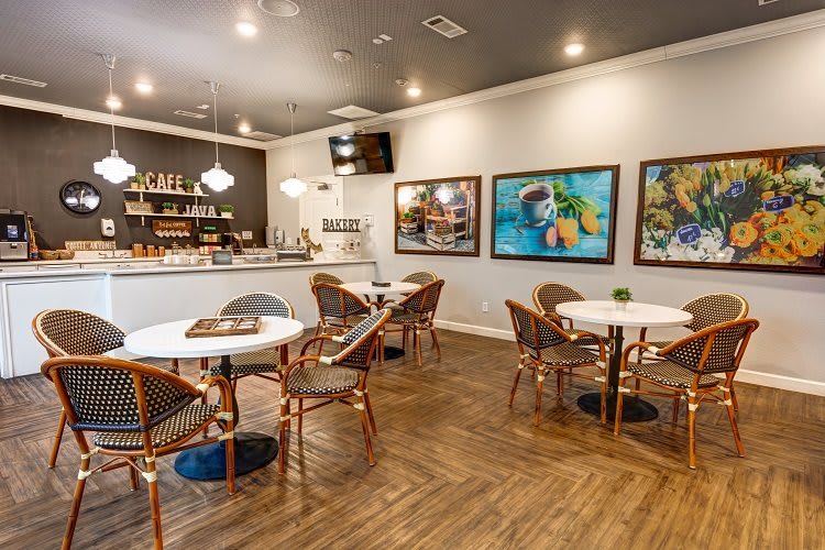 A cozy cafe interior with round tables and art-adorned walls.