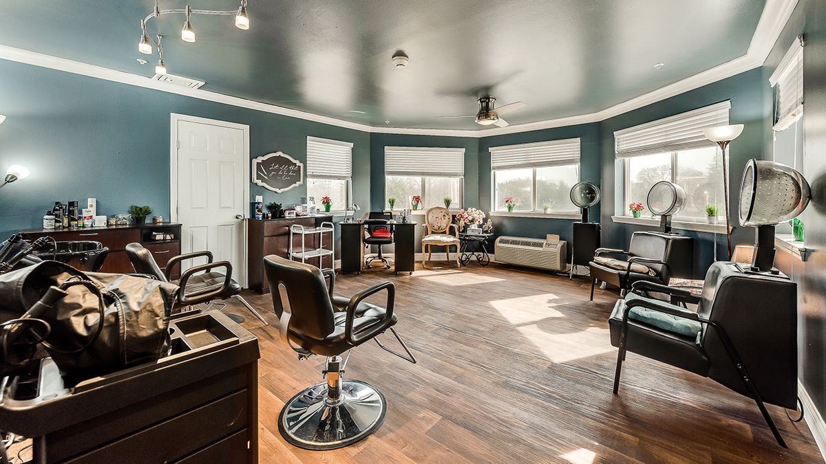A modern and spacious beauty salon with chairs, mirrors, and large windows.