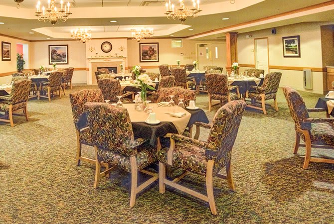 An elegant dining room with neatly arranged tables and chairs, featuring floral centerpieces.