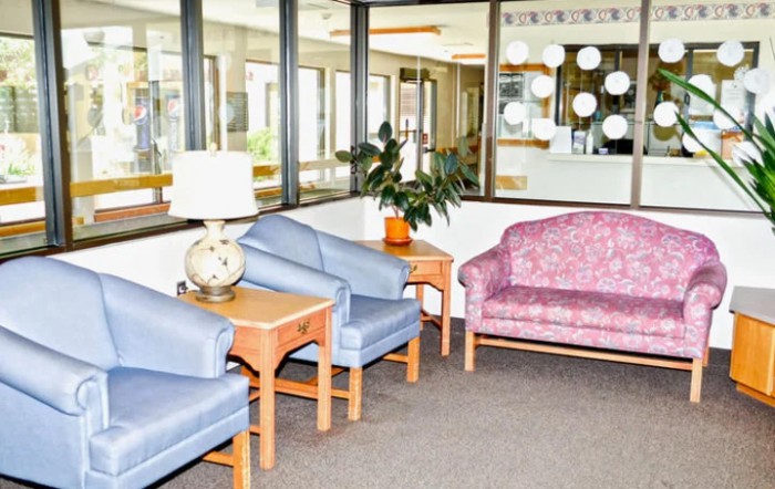 A lobby area with a seating arrangement consisting of blue chairs and a pink sofa.
