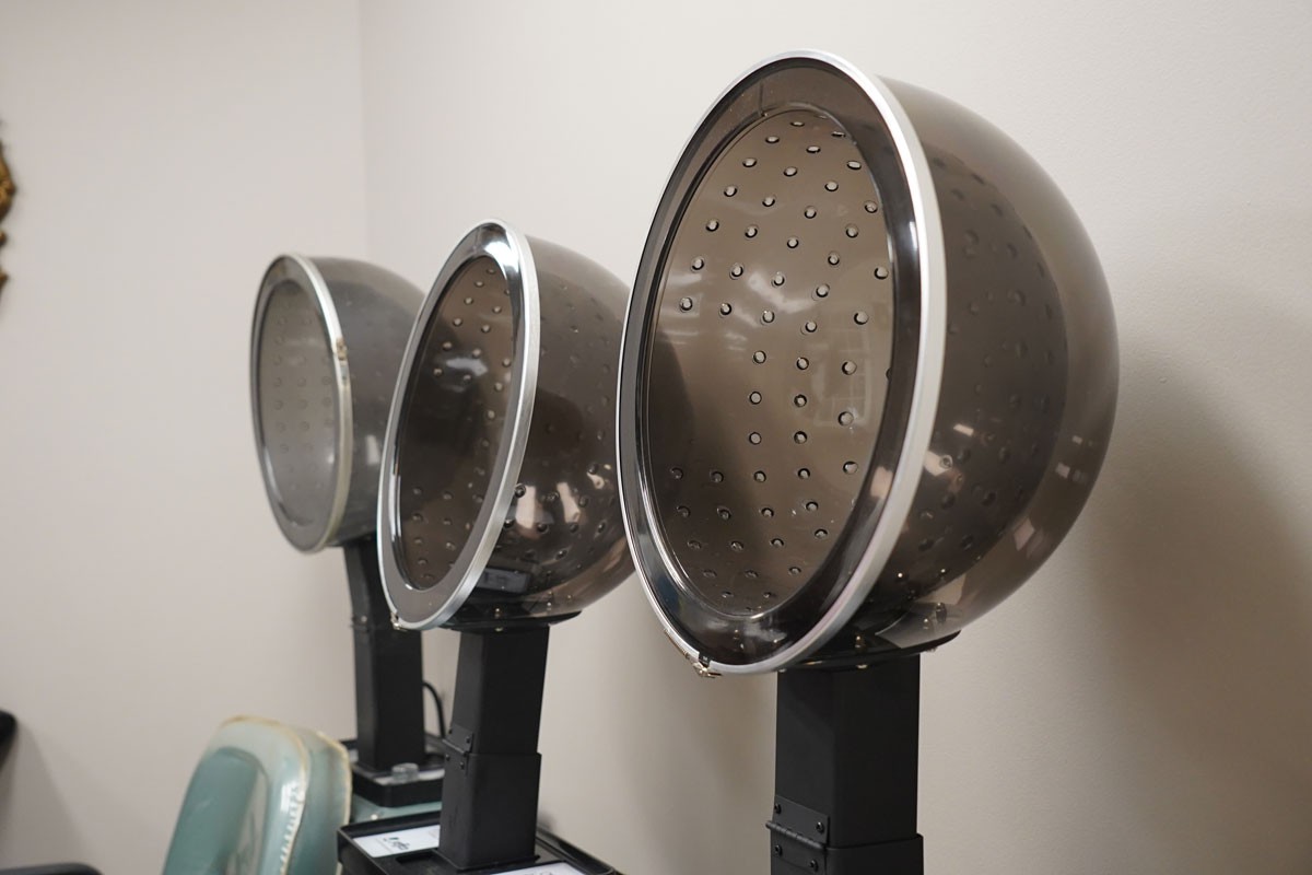 Row of hair dryers in a salon setting.