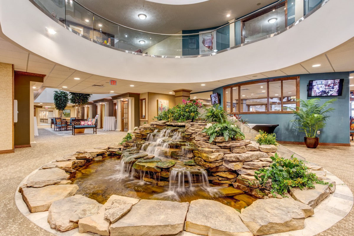 A beautifully designed lobby featuring an indoor waterfall surrounded by rocks and plants.
