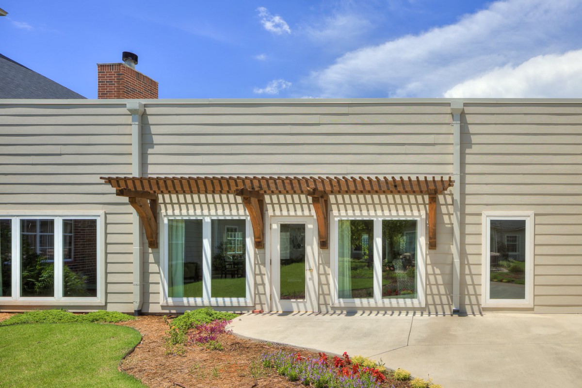 A modern house exterior with a pergola and sliding glass doors leading to a patio.