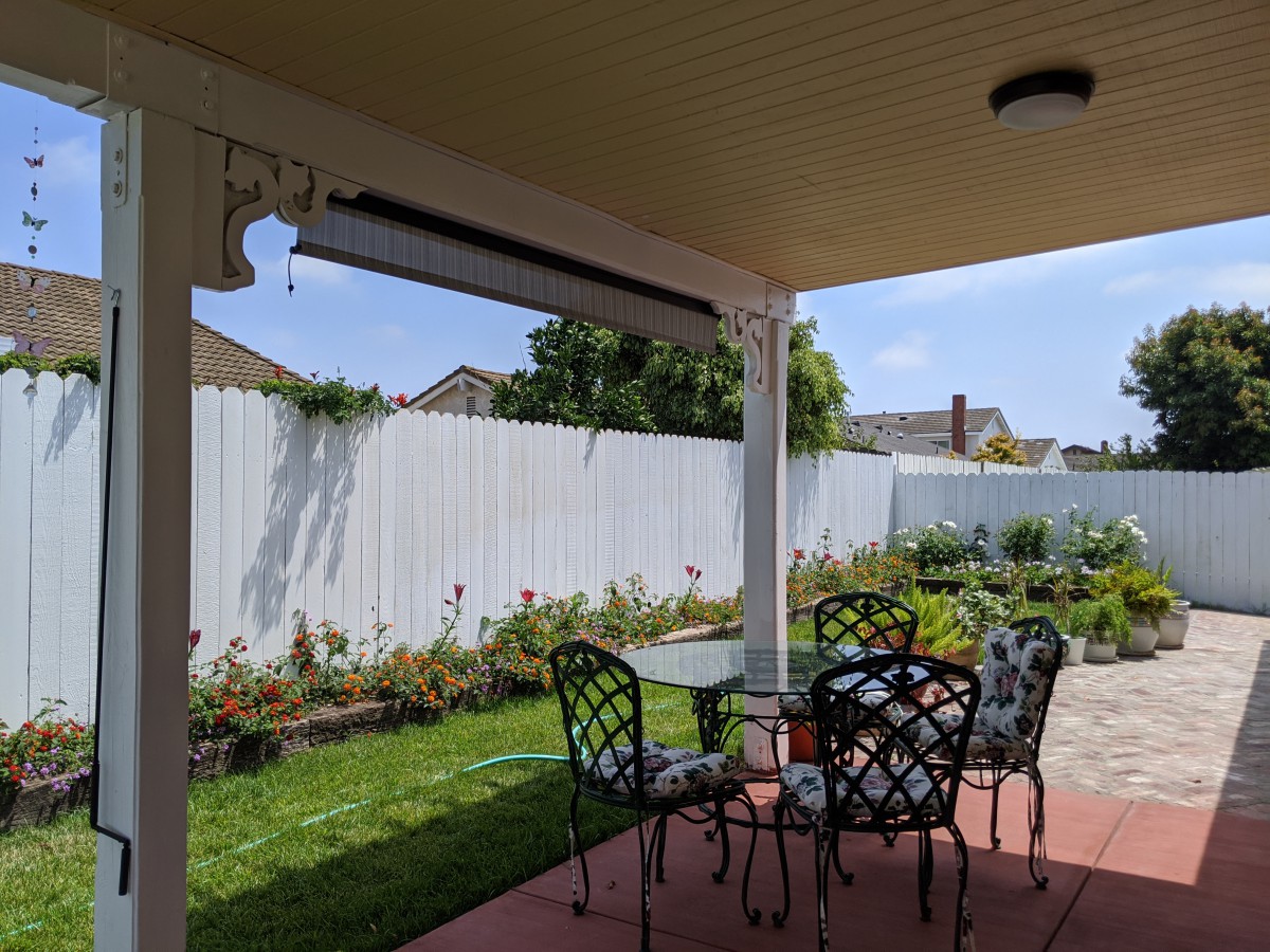 A cozy patio area with outdoor furniture overlooking a garden on a sunny day.