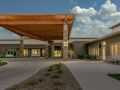 A modern building with a large entrance and an extended canopy under a partly cloudy sky.
