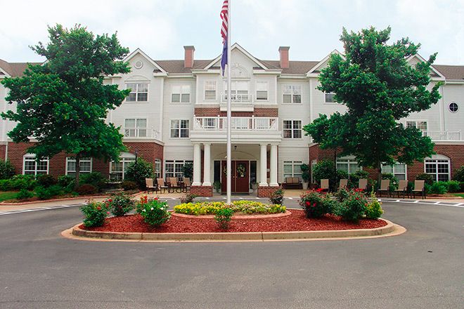 A hotel with a landscaped entrance and flagpole.