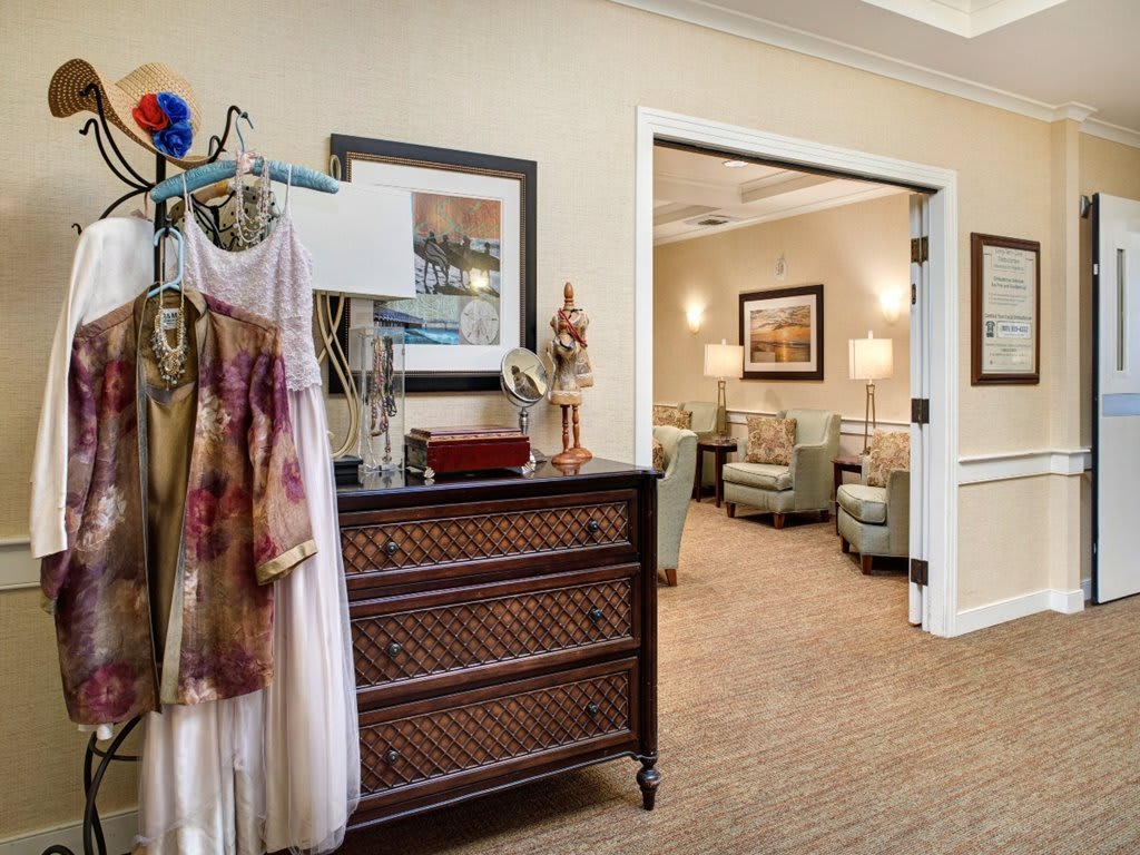 A cozy interior space featuring a selection of dresses, elegant furniture, and artwork on the walls.