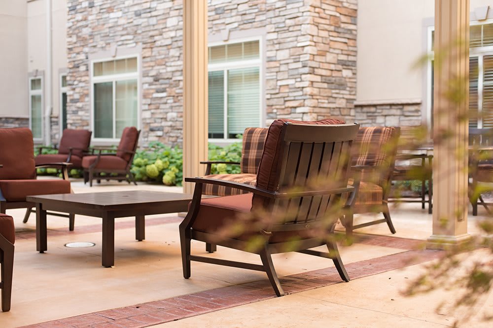 A cozy outdoor patio area with lounge chairs and a stone wall backdrop.