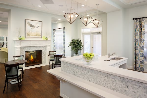 A modern kitchen with a stylish countertop, pendant lights, and a cozy fireplace.