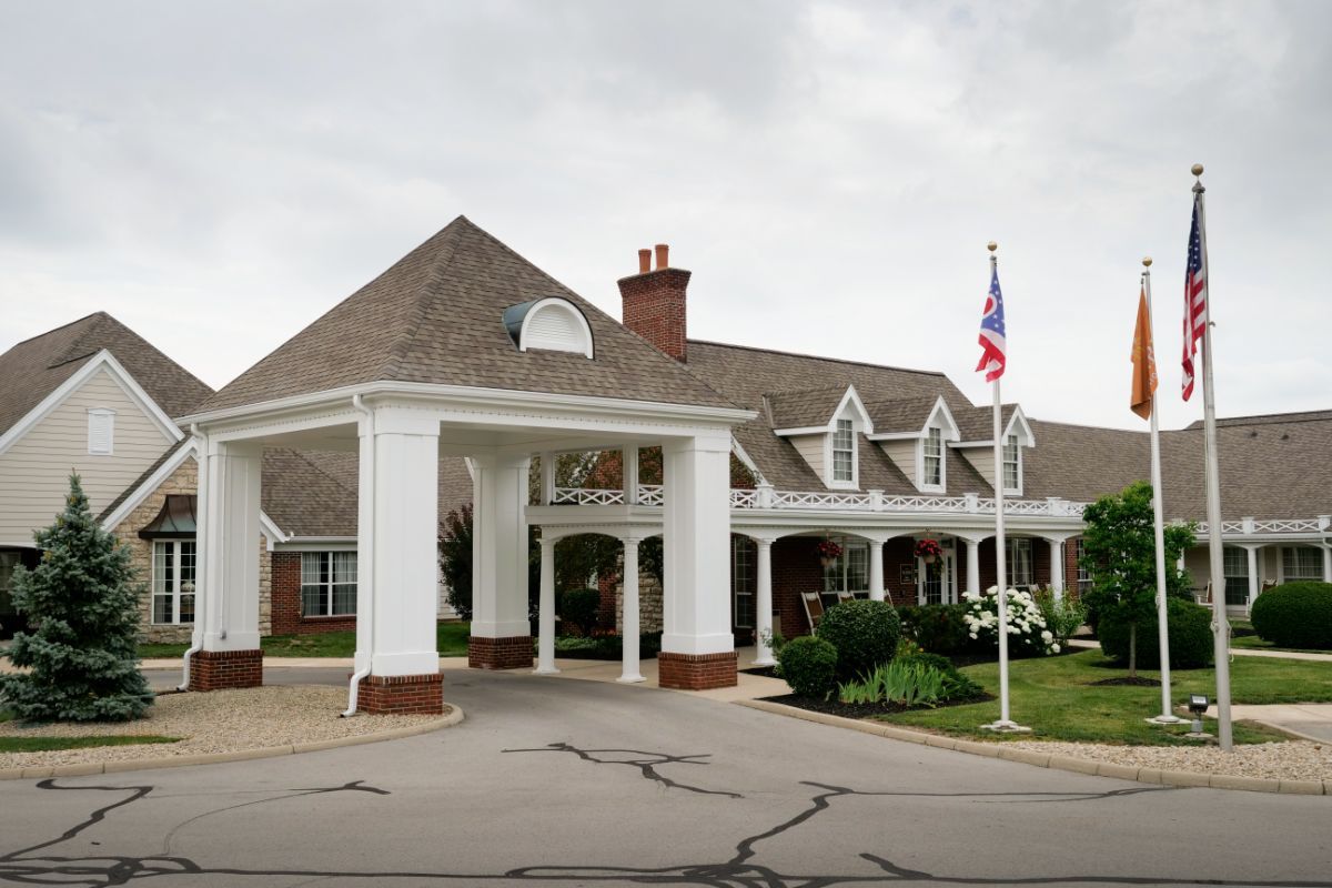 A large house with a covered driveway and an American flag on display.