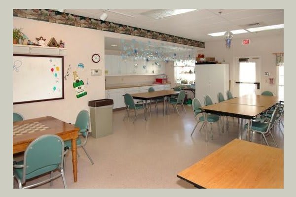 An empty classroom with tables and chairs arranged neatly, decorated walls, and bright lighting.