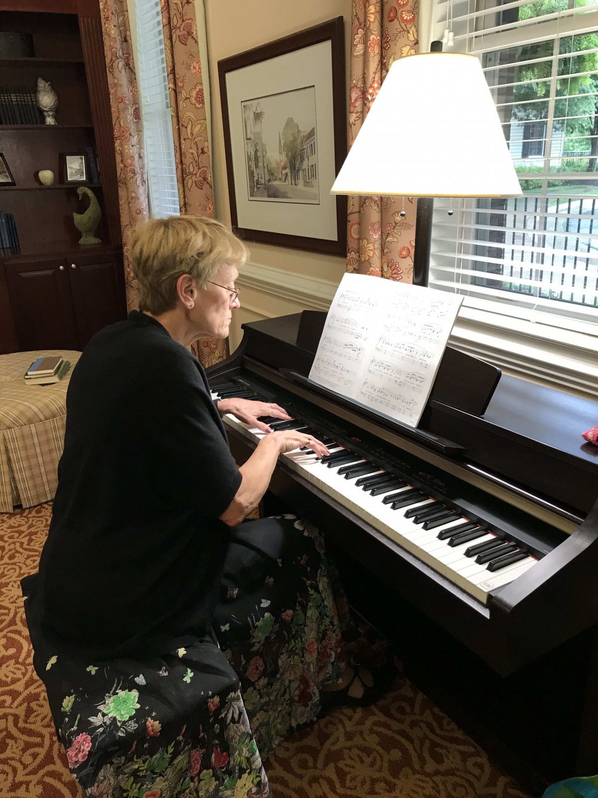 A woman playing the piano with sheet music in front of her.