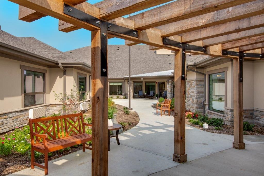 A serene courtyard with wooden pergola and outdoor seating surrounded by stone buildings.