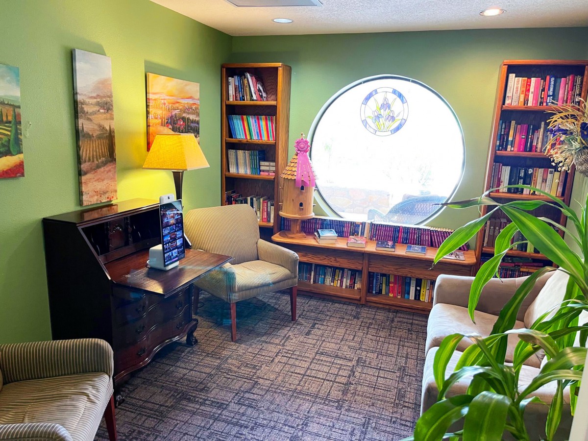 A cozy reading room with bookshelves, comfortable chairs, and a bright circular window.