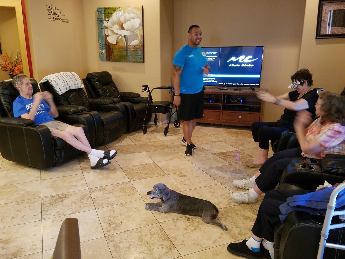A group of people relaxing in a living room with a dog lying on the floor.