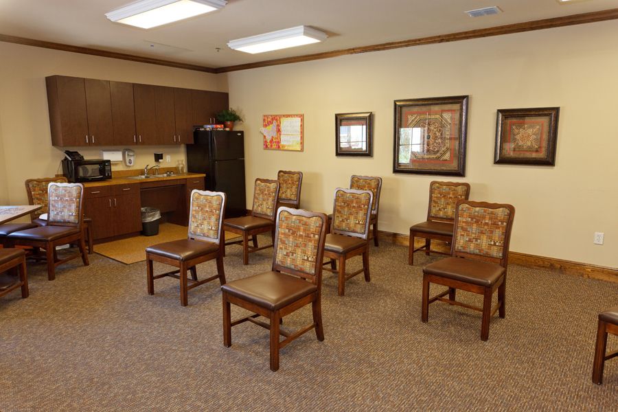 A small waiting room with arranged chairs and a kitchenette in the corner.