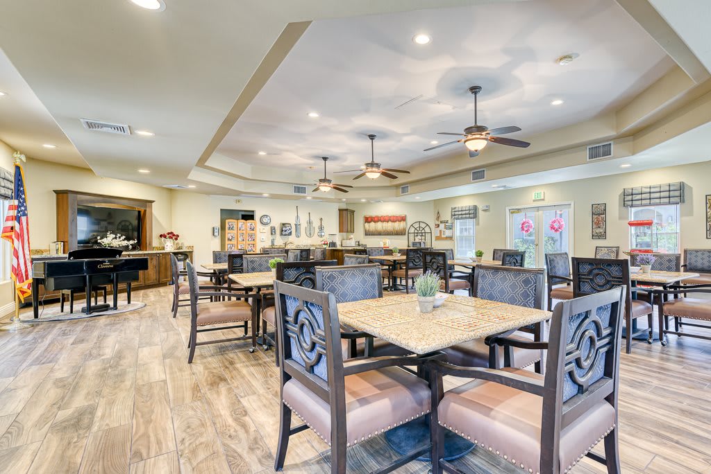 A spacious and modern dining area featuring stylish furniture, warm lighting, and ceiling fans.