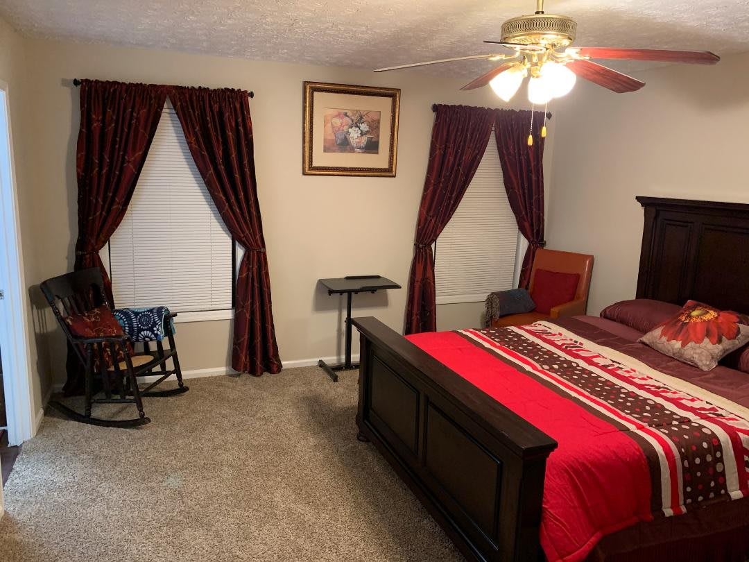 A cozy bedroom with a red-themed decor and a ceiling fan.