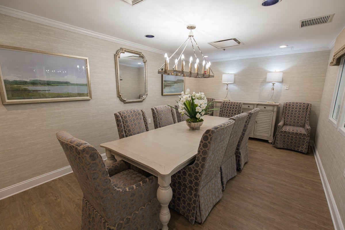 Elegant dining room with a long table, upholstered chairs, and a chandelier.