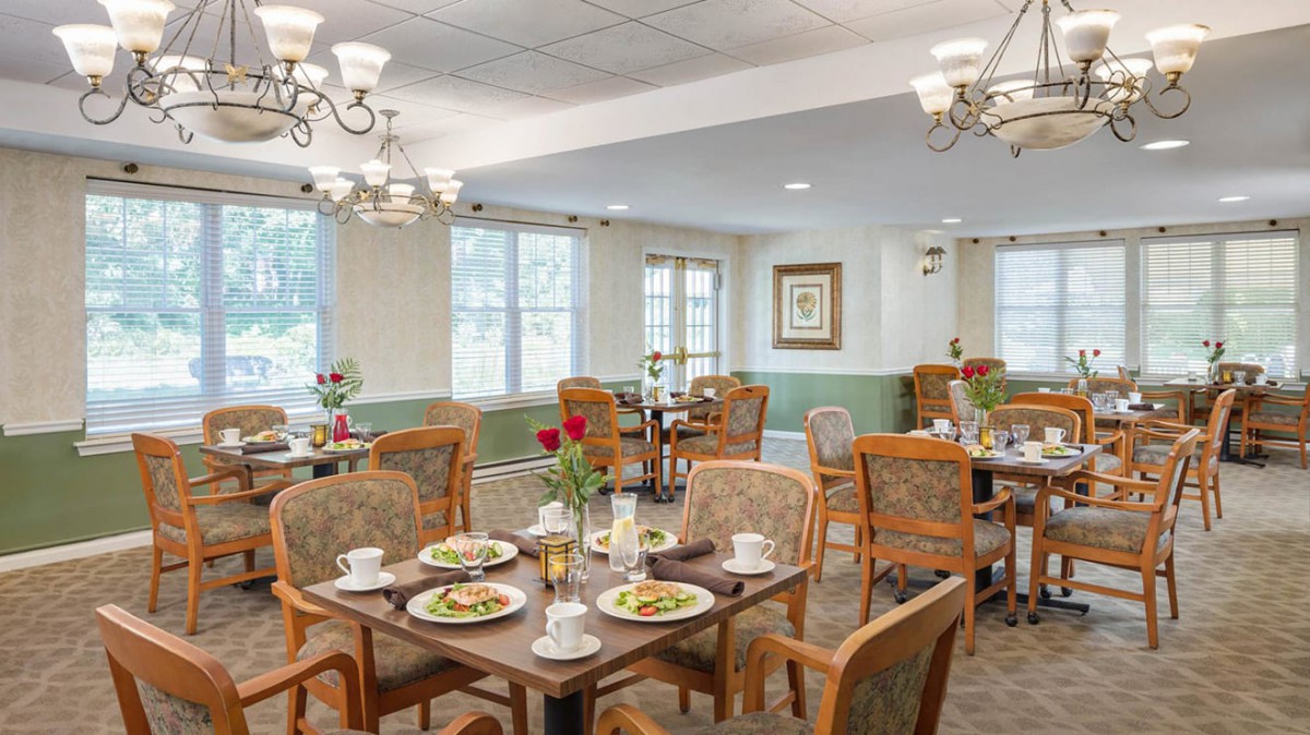 A cozy dining room with neatly arranged tables and elegant chandeliers.