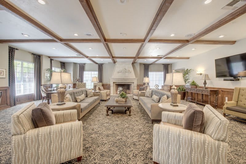 A spacious and elegantly designed living room with multiple sofas, a central fireplace, and warm lighting.