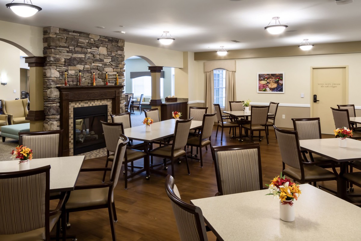 A cozy dining area with neatly arranged tables and a warm fireplace.