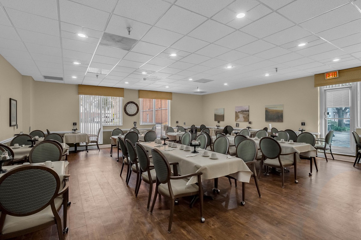 An empty dining room with neatly arranged tables and chairs, featuring warm lighting.