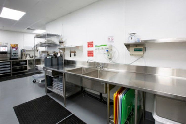 A well-organized commercial kitchen with stainless steel fixtures and multiple sinks.