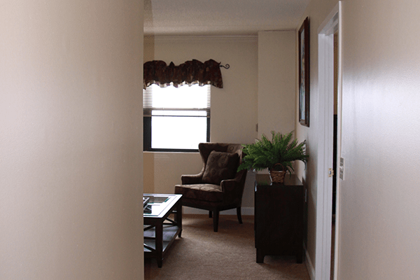 A cozy living room with a chair, table, and window.