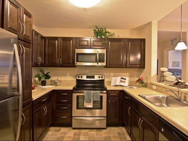 A modern kitchen featuring dark wooden cabinets and stainless steel appliances.