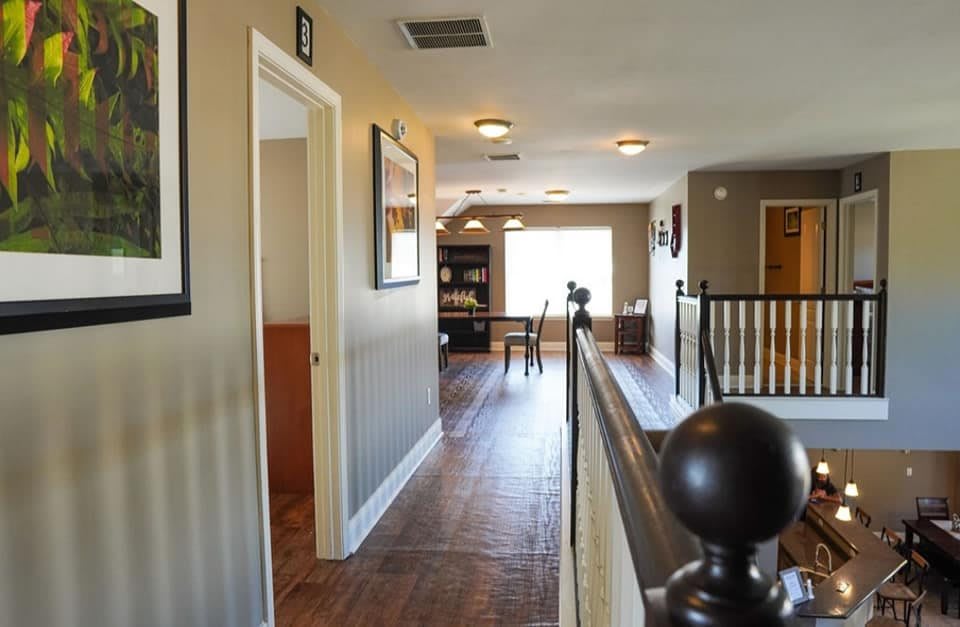 A cozy hallway in a house featuring wooden floors and natural lighting.