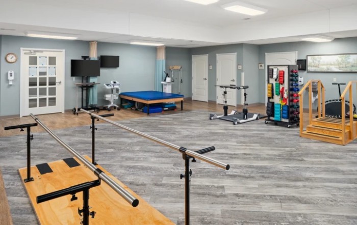 A spacious rehabilitation room equipped with parallel bars and various exercise equipment.