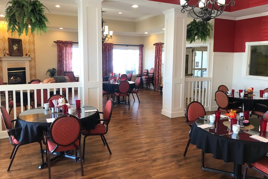 A cozy dining area with wooden floors and red-themed decor features elegant tables and chairs.
