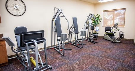 A gym with various exercise machines lined up against the wall.