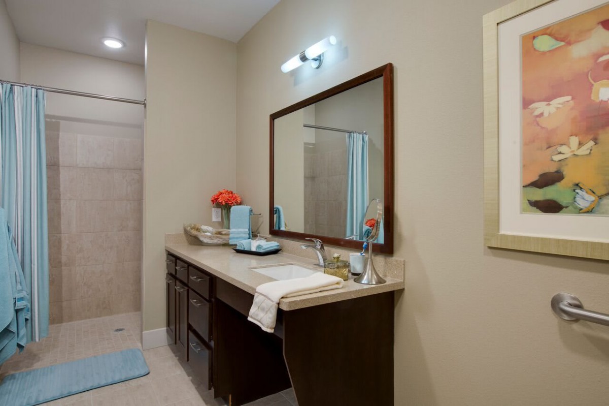 A well-organized bathroom with a large mirror and countertop featuring decorative items.